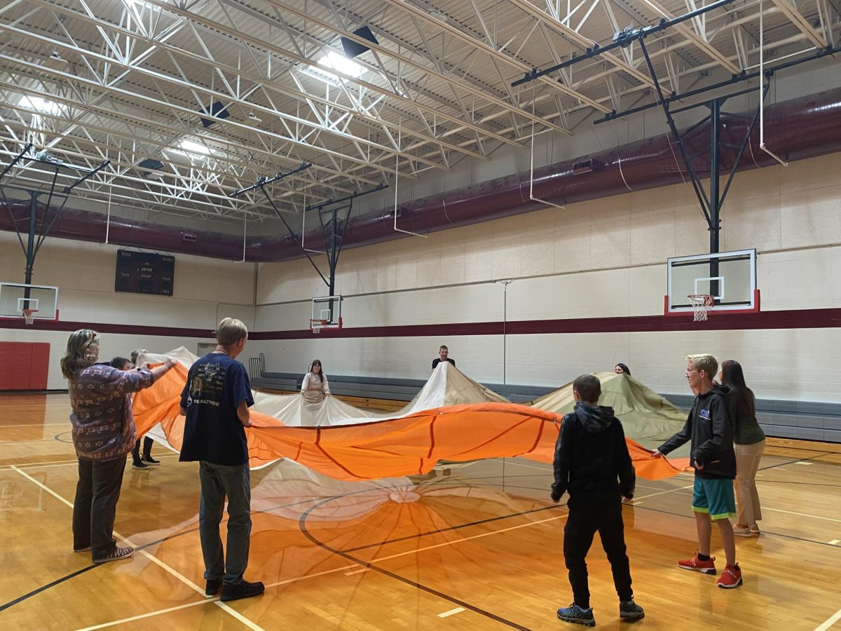 CIRCLE UP: Special Olympians have fun playing with a parachute in the aux gym. The photo is reminiscent of the Special Olympics logo showing figures holding hands in a circle of unity.
