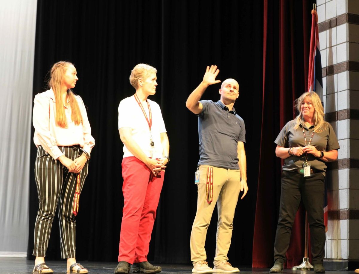 NEW KIDS ON THE BLOCK: Mr. Bryan Burton waves to the student body at the Welcome Back Assembly in August. He is joined on the stage by other new teachers.