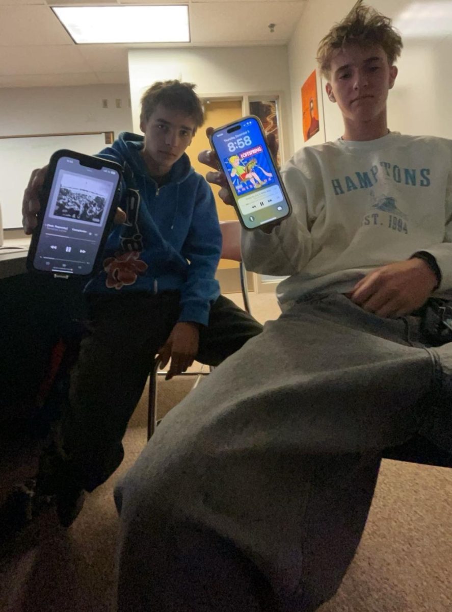 PODLESS: Owen Lancaster and Rhen England show what they are missing while working in class. School policy restricts the use of phones and earphones from bell to bell. "No AirPods makes me hate school even more now," said Lancaster. "No phones is understandable, and honestly I don't care about it that much, but the no AirPods rule seems kind of stupid," added England.