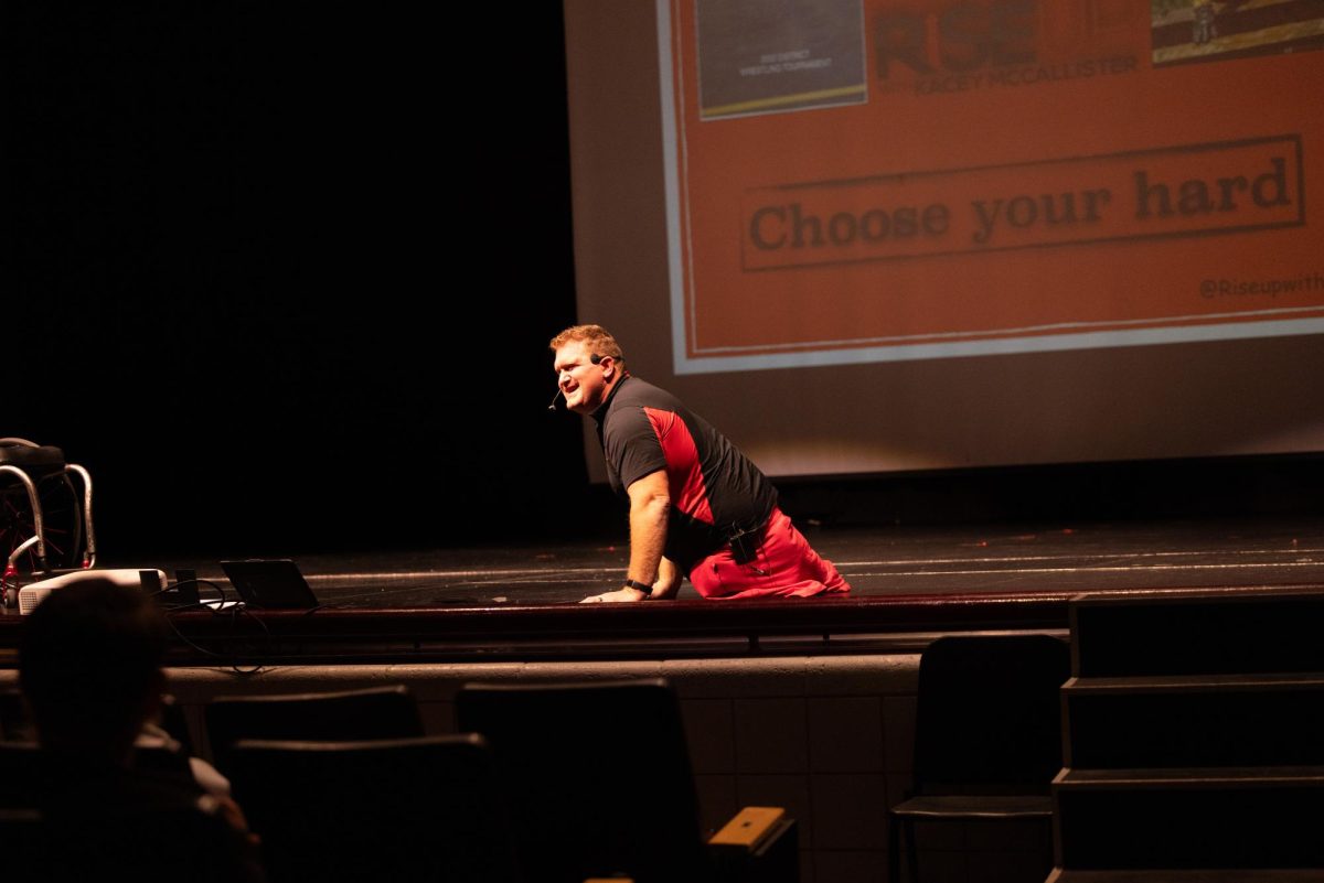 Kacey McCallister takes the auditorium stage for an assembly. He shared his story of trying to push through and overcome the challenges that he faced after losing his legs.