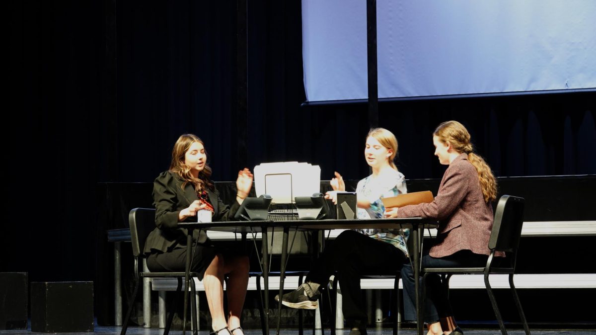 (Left to right) Seniors Karlee Rosa, Lily Keith, and Mary Johnson acting out the lives of workers in the towers. The scene is a normal morning meeting before the first tower was struck. This was a tragic day for all Americans.