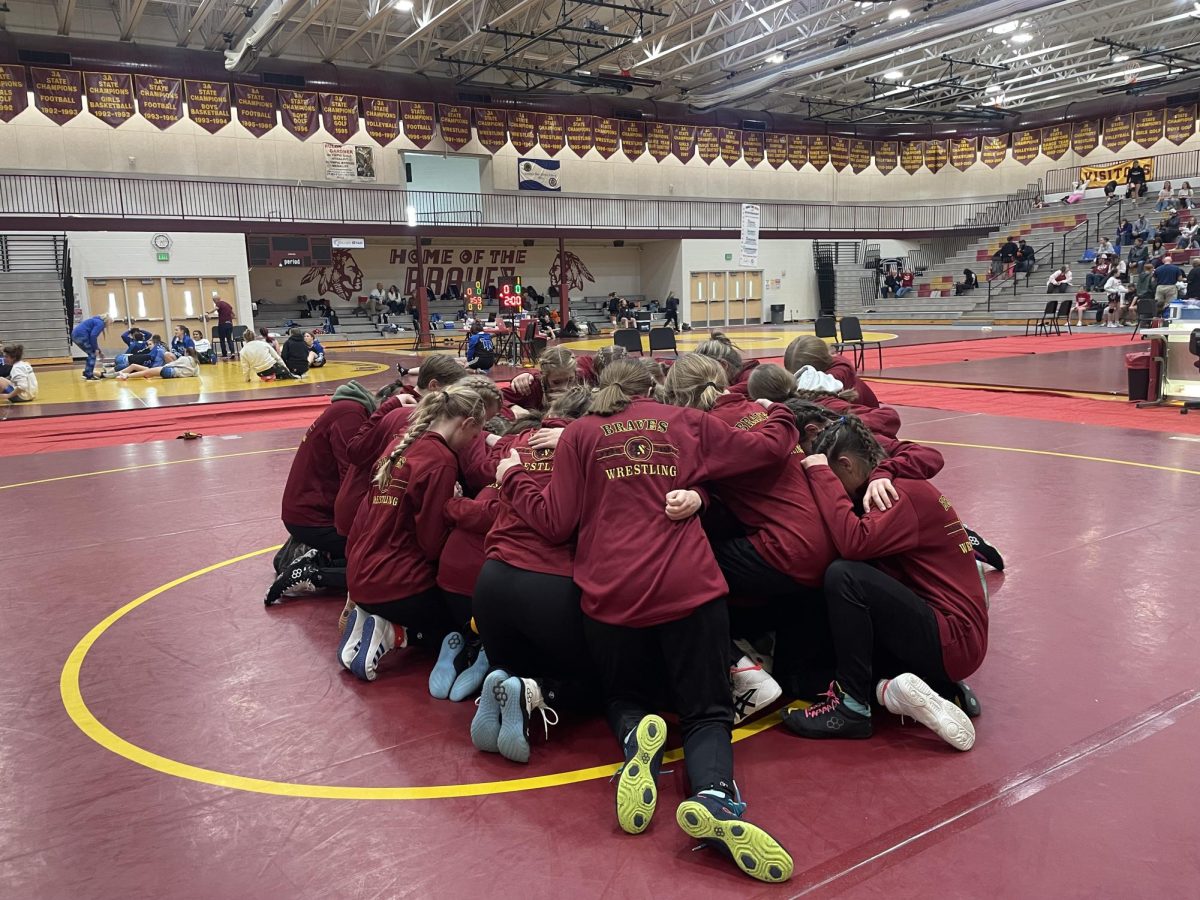 The Lady Braves wrestlers huddle together at a home meet during last year's season. They are the only team to ever win the WY state girls championship and will go for 4 in a row this year. 