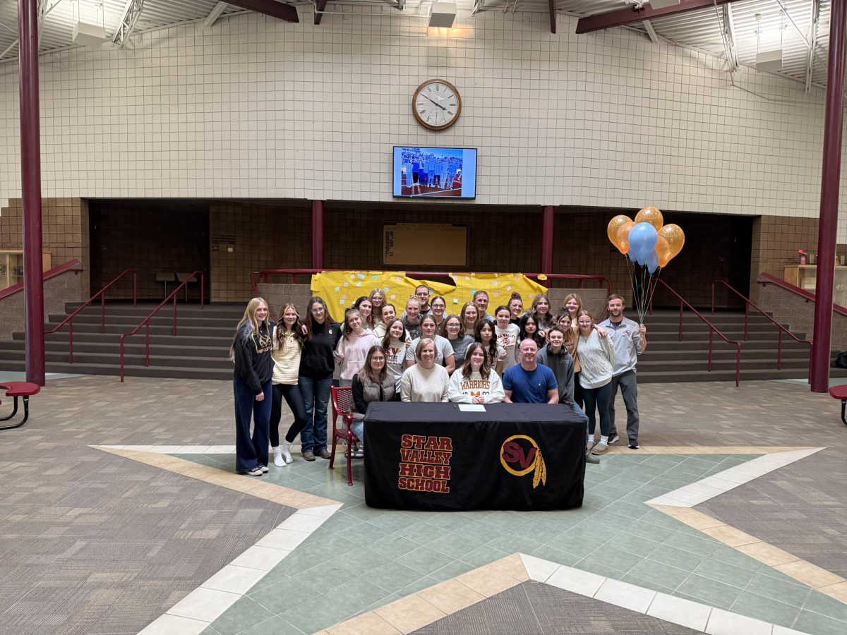 The Lady Braves wrestling team stands in a picture to congratulate Cara Andrews on her success of signing to go to college for wrestling in Nebraska.