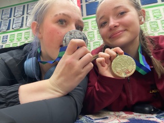 Freshman Sophia Bauer and sophomore Brinn Mizner show off their medals from the Lady Hawk Challenge. Sophia succeeded at winning first, and Brinn won second in her weight.