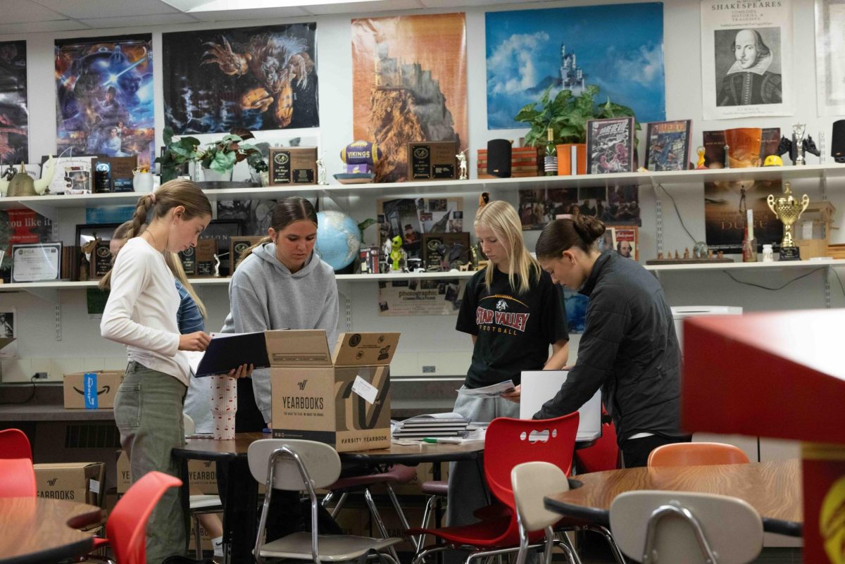 During the first week of May, yearbook staff members work together to glue spring event pages into the yearbook — a process repeated 715 times to prepare every copy for distribution.